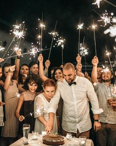 a group of people standing around a table holding sparklers