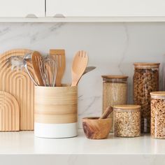 kitchen utensils and wooden spoons in containers on a countertop with marble background