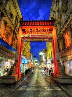 an archway in the middle of a street with people walking under it at night time