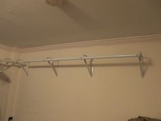 an empty closet with clothes hanging from the ceiling and two white hangers on the wall