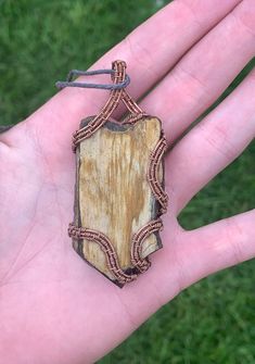 a hand holding a piece of wood with a string around it and a wooden plaque on top