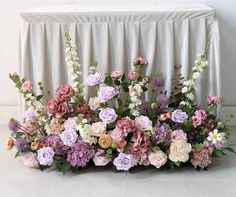 an arrangement of flowers is displayed on a white tablecloth draped over the headboard