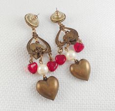 These Victorian Revival drop hearts earrings are stunning with a top faux Mabe pearl in a filigree circle, an open inverted etched heart with a dangle brass heart with a prong-set red stone, two dangle red glass hearts, a faux pearl bead and a bottom large puffy brass heart. They are spectacular!! measure 2 7/8 from the top of the wire to the bottom of the beads and measure 5/8 in width are pierced post earrings and light weight are in excellent condition and look awesome on! are so very beautif Valentine Earrings, Hearts Earrings, Peace Sign Necklace, Glass Hearts, Goth Necklace, Horse Earrings, Valentines Earrings, Victorian Revival, Halloween Necklace