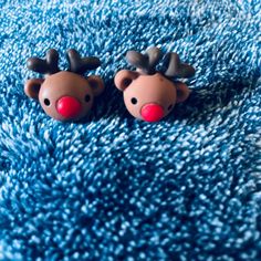 two brown reindeer head earrings laying on top of a blue rug