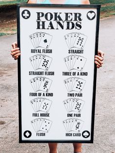 a person holding up a sign with some playing cards on it's front side