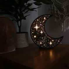 a wooden table topped with a lit up moon next to a potted green plant