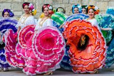 women in brightly colored dresses and headdresses are dancing