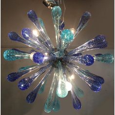 a blue chandelier hanging from the ceiling with lights on it's sides