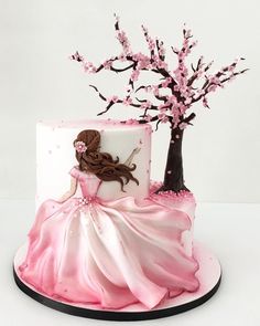 the cake is decorated with pink icing and has a woman in a dress on it