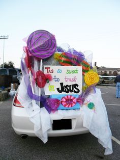 a car covered in lots of stuff sitting on top of a parking lot next to a sign