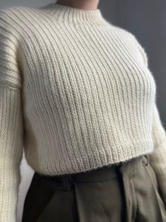 a mannequin wearing a white sweater and khaki pants with buttons on the side