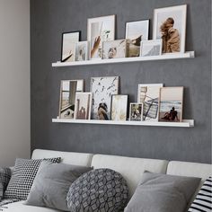 a white couch sitting next to a wall with pictures on the wall and pillows in front of it