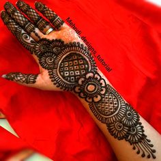 a woman's hand with henna tattoos on it and red fabric in the background