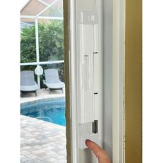 a person is holding the door handle on a sliding glass door near a swimming pool