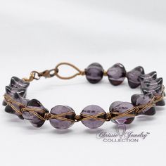 a bracelet with purple glass beads and gold wire