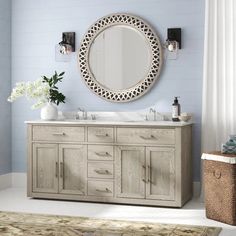 a bathroom with blue walls and a large round mirror on the wall above the sink