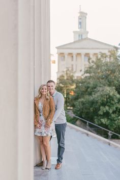 an engaged couple standing next to each other in front of the columns at the capitol building