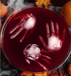 two hands made out of ice on top of a glass bowl filled with red liquid