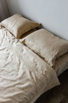 an unmade bed with two pillows on the bottom and one pillow on the top