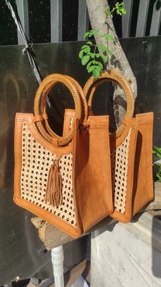 This elegant tote blends natural rattan and cane with a sleek top handle, offering a unique style perfect for any occasion. Enjoy free shipping on our collection of handcrafted rattan handbags. Each rattan bag is carefully handmade by skilled artisans from Indonesia. Crafted with attention to detail, combining rattan with a soft polyester lining. Features a secure snap closure, ensuring your belongings stay in place. Rattan bag dimensions: 11" (H) x 14" (W) x 4" (D). Handle drop: 5.5" with a handle length of 12" for a comfortable grip. Each rattan bag takes approximately 7-10 business days to complete, reflecting the time invested in its creation. Its eye-catching design adds a touch of nature to your look. Elegant Rattan Handbag for Every Occasion Add a touch of natural charm to your ever Rattan Bags, Cane Webbing, Rattan Handbags, Patchwork Cowhide Rug, Brindle Cowhide, Rattan Weave, Mens Leather Pants, Leather Toiletry Bag, Leather Waist Bag