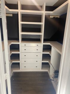 an empty walk in closet with white shelves and black walls is seen from the doorway