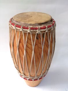 a large wooden drum with red strings on it's sides, sitting on a white surface