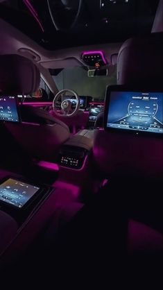 the interior of a car with purple lighting and electronic gadgets on display in the front seat