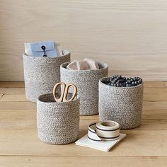 three different types of baskets on a wooden table with scissors and other items in them