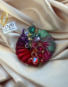 a colorful brooch sitting on top of a white cloth