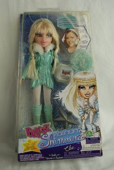 the doll has blonde hair and is wearing green clothes with fur on her head,