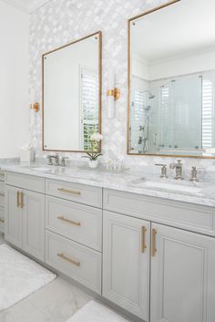 a large bathroom with two sinks and mirrors on the wall, along with white rugs