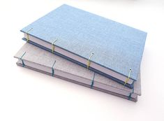 two books are stacked on top of each other, one is blue and the other is gray