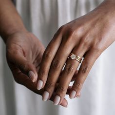 a close up of a person's hands with two wedding rings on their fingers