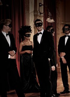 a group of people in tuxedos wearing blindfolds and standing around each other