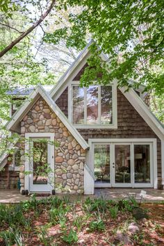 a small stone house surrounded by trees in the woods