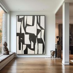 an abstract painting hangs on the wall next to a bench in front of a large window