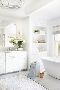 a bathroom with white cabinets and marble counter tops, along with a large bathtub