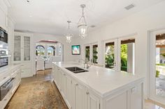 a large kitchen with white cabinets and marble counter tops