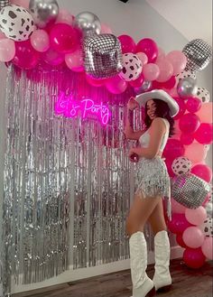 a woman standing in front of balloons and disco balls