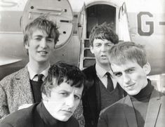 four young men standing next to each other in front of an airplane