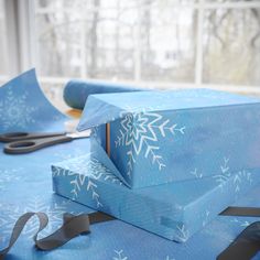 blue wrapping paper with white snowflakes on it and scissors sitting next to it