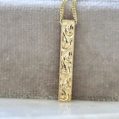 Why I Love It: Look no farther for an ultra sleek, modern piece! This vertical bar necklace hands from a perfectly luxe 16 inch curb chain and feature both hand engraved scroll detail and milgrain on the borders. This is the perfect summer treat! All in 14k Yellow Gold. The Details: 14k Yellow Gold 16 in. Curb Chain Hand Engraved Detail Measures 3.34 x 19.94 mm What You Need To Know: Have more questions? Perhaps our FAQ page will help! Luxury Engraved Classic Necklace, Luxury Statement Engraved Jewelry, Luxury Classic Engraved Necklaces, Exquisite Luxury Engraved Jewelry, Luxury Timeless Engraved Necklace, Luxury Exquisite Engraved Jewelry, Luxury Engraved Collectible Jewelry, Luxury Collectible Engraved Jewelry, Luxury Engraved Gold Plated Chain Necklace