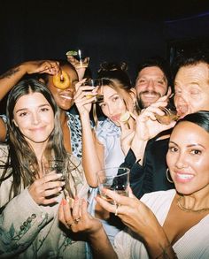 a group of people posing for a photo with drinks and doughnuts in their hands