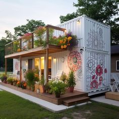 a house made out of shipping containers with flowers on the balcony