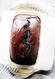 a loaf of chocolate cake sitting on top of a white and gray towel next to a can