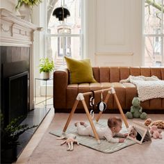 a baby laying on the floor in front of a couch with stuffed animals around it