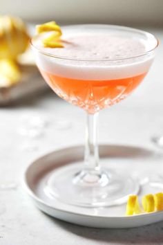 a drink in a glass with lemon wedges next to it on a white plate