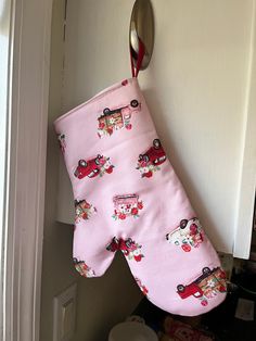 a pink oven mitt hanging on the wall with a spoon in it and a red firetruck