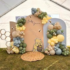 a balloon arch with winnie the pooh and honeycombs on it in front of a white tent