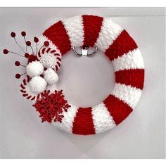 a red and white knitted wreath with pom - poms